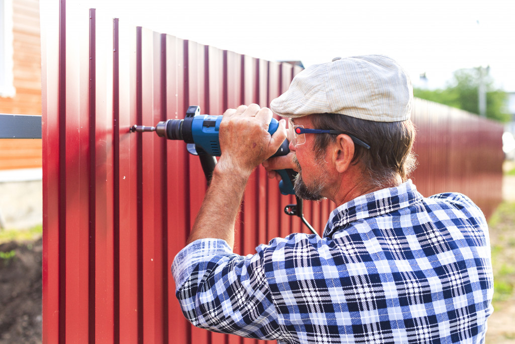 elderly man with a drill building a fence