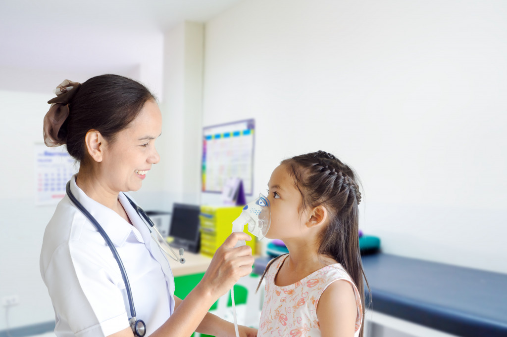 woman putting a oxygen mask on a little girl