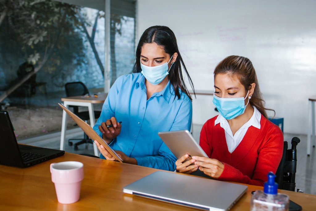 two women wearing facemask assessing their investments