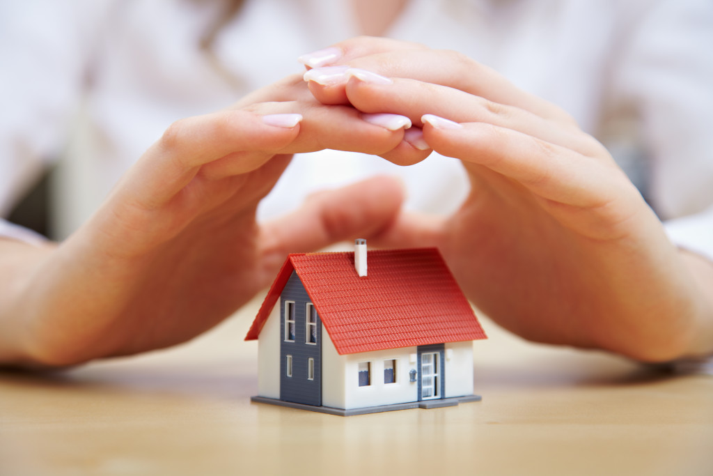 A person holding their hands over a miniature house
